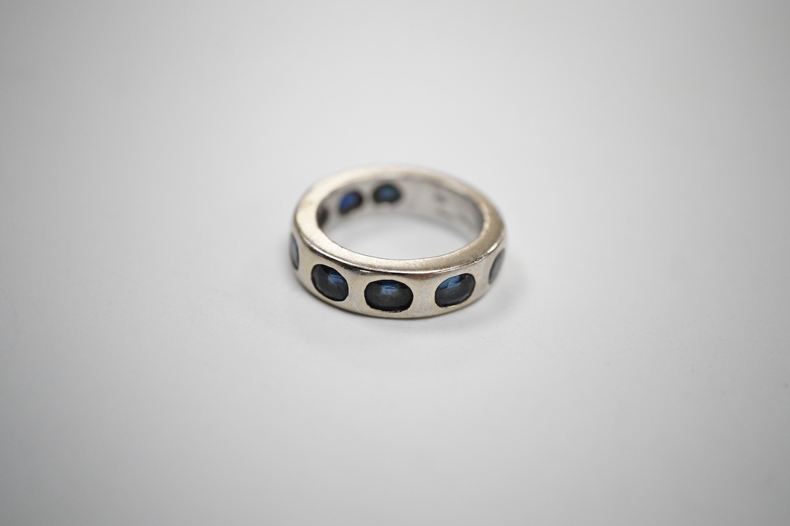 A recent Italian white metal (stamped 750) and seven stone gypsy set oval cut sapphire band, by Cristiano of Genoa, size N, gross weight 10.4 grams.